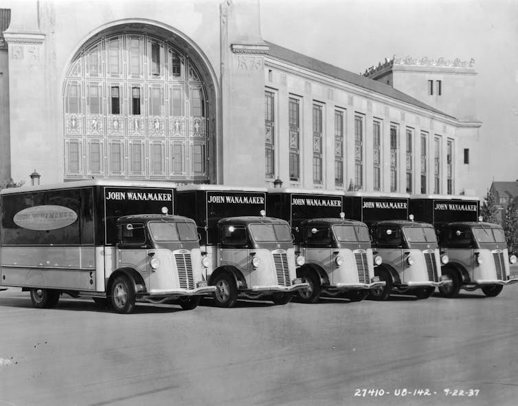 A black-and-white photo shows a fleet of delivery trucks for the John Wanamaker Department Store parked side by side.