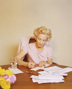An older lady writes out checks to pay bills.