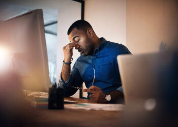 Shot of a young businessman looking stressed out while working in an office at night