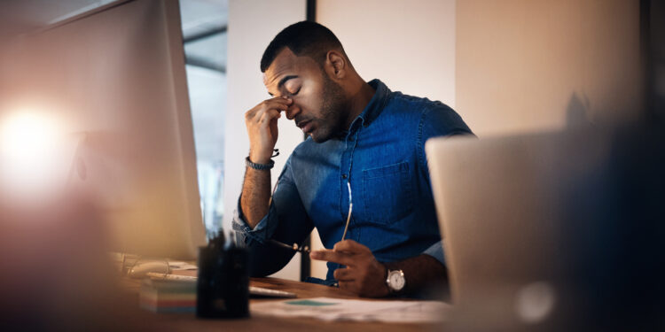Shot of a young businessman looking stressed out while working in an office at night